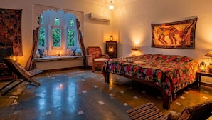 A room with a large bed, a window with decorative shutters, a chair, and a tapestry on the wall. - Hibiscus Heritage - A Lake View Hotel in Udaipur (Udaipur)