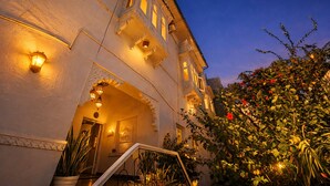 A building with ornate architectural details, including a balcony with a railing and a staircase leading to an entrance. - Hibiscus Heritage - A Lake View Hotel in Udaipur (Udaipur)