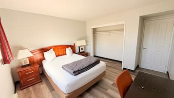 Quarto de hotel com cama, mesas de cabeceira, escrivaninha e guarda-roupa.