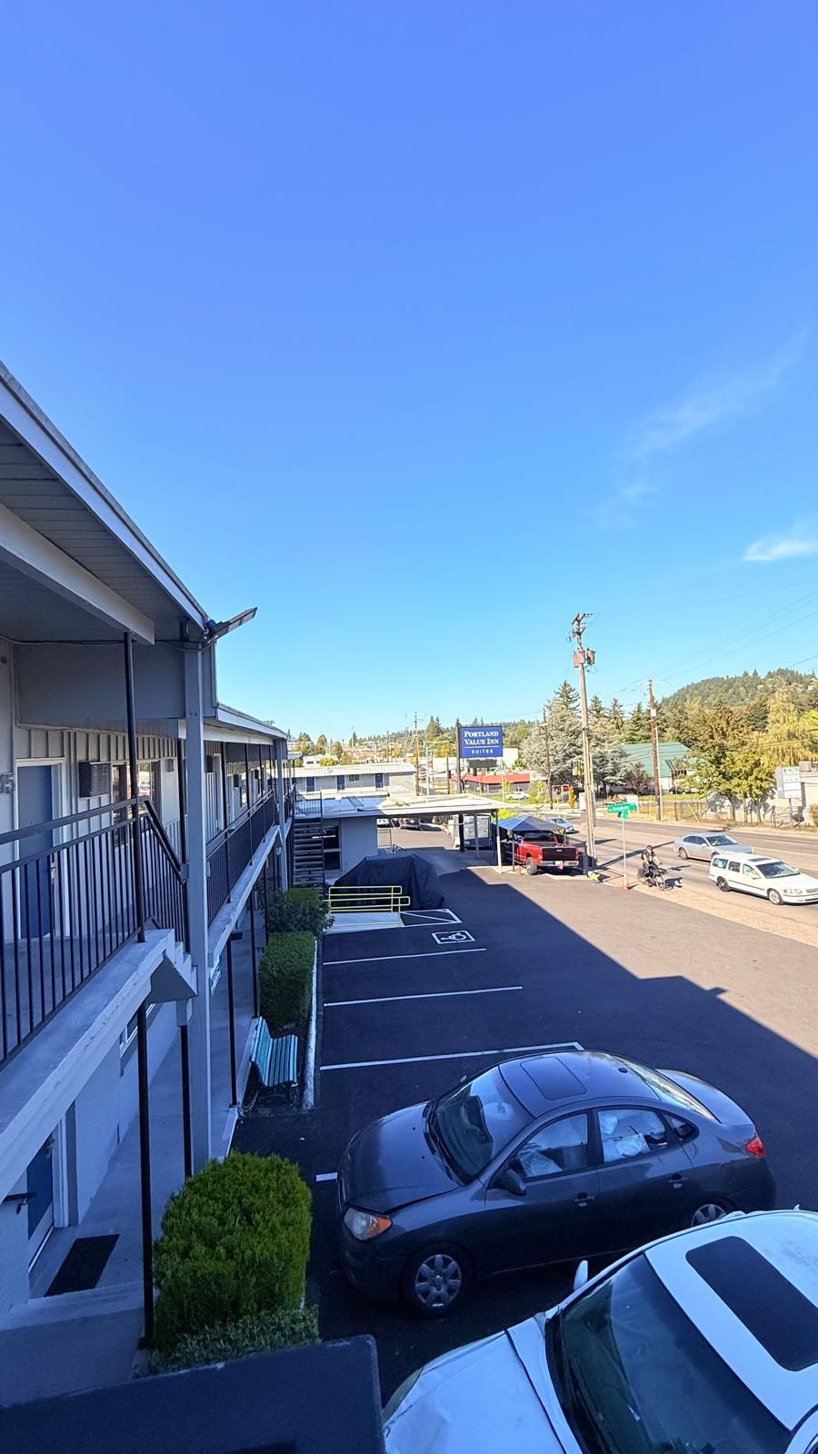 A parking lot with a motel building on the left, a covered area, and a sign for Portland Value Inn Suites.