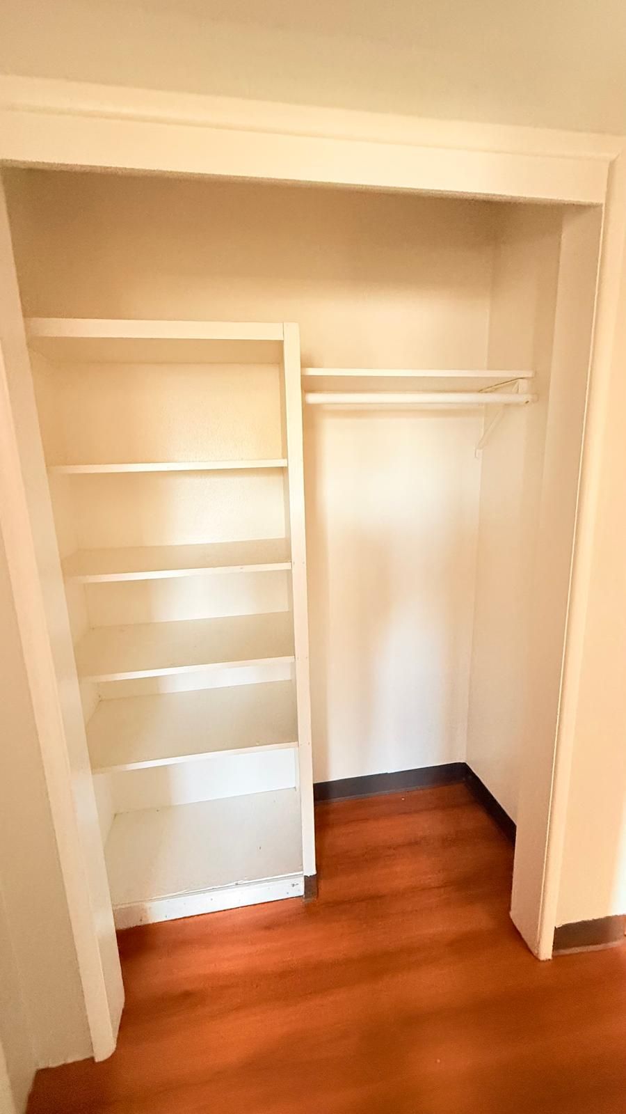A walk-in closet with open shelves and a hanging rod.