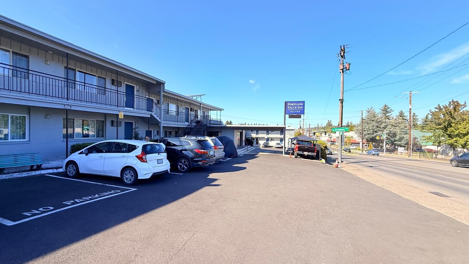 Un estacionamiento con un motel llamado 'Portland Value Inn' y un cartel que indica 'Broadway St'.