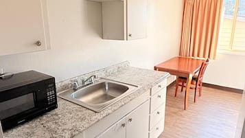 Una cocina compacta con microondas, fregadero y armarios.