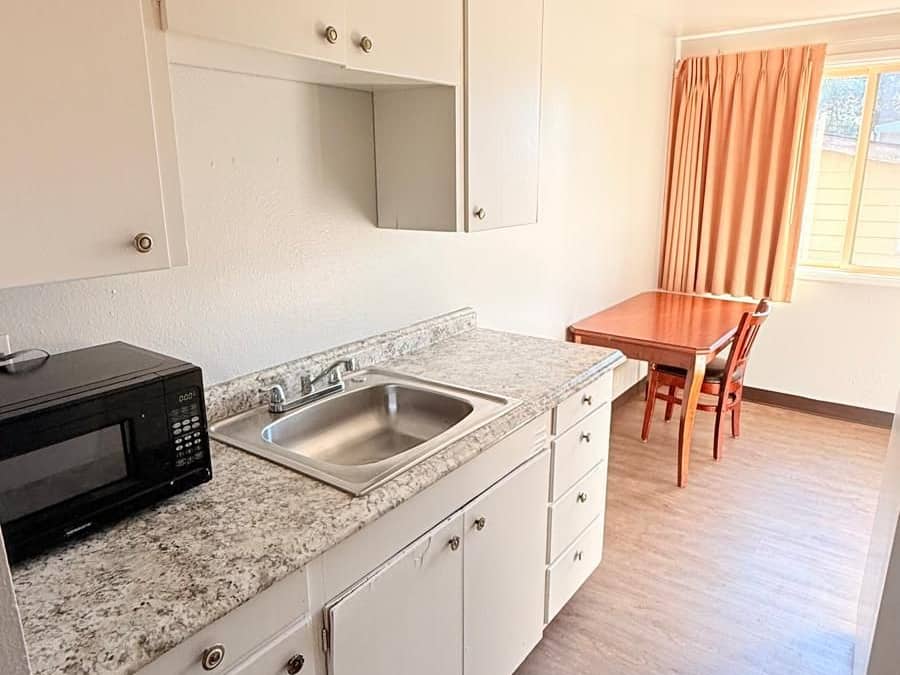 A compact kitchen with a microwave, sink, and cabinets.