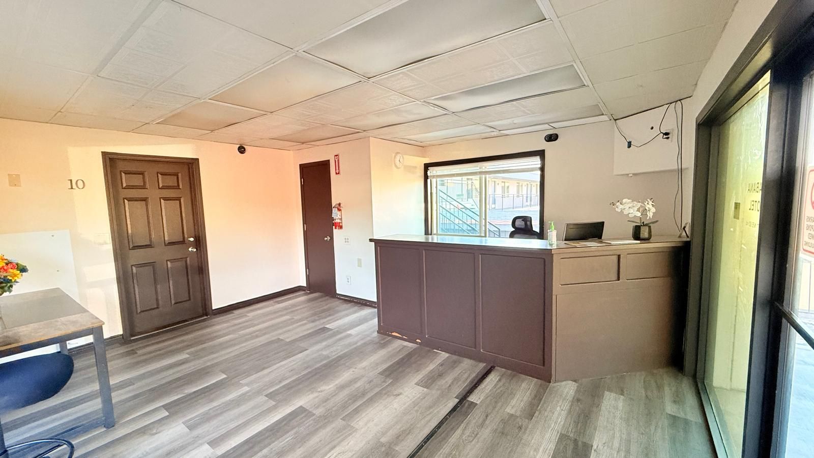 A reception area with a desk, a door, and a window with a view of buildings.