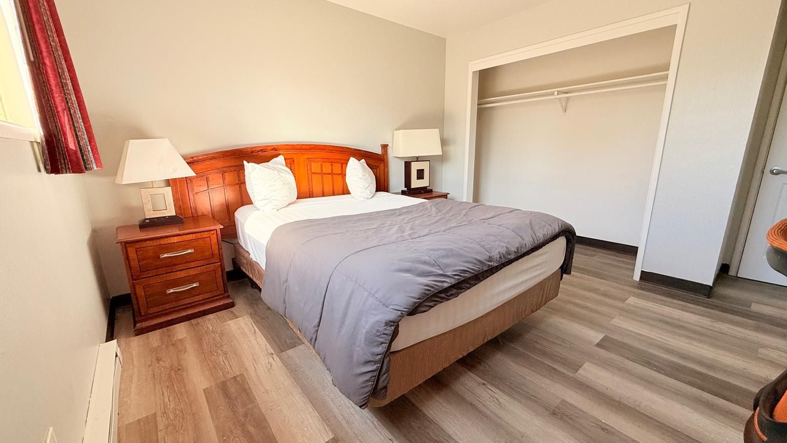 A hotel room with a bed, bedside tables, a wardrobe, and a door.