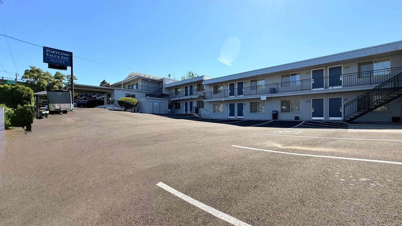 A motel with multiple suites, a parking lot, and a clear sky.