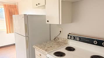 A kitchen with white cabinets, a white refrigerator, a stove with four burners, and a vent on the ceiling.