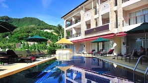 Una piscina al aire libre, sombrillas, sillones reclinables de piscina