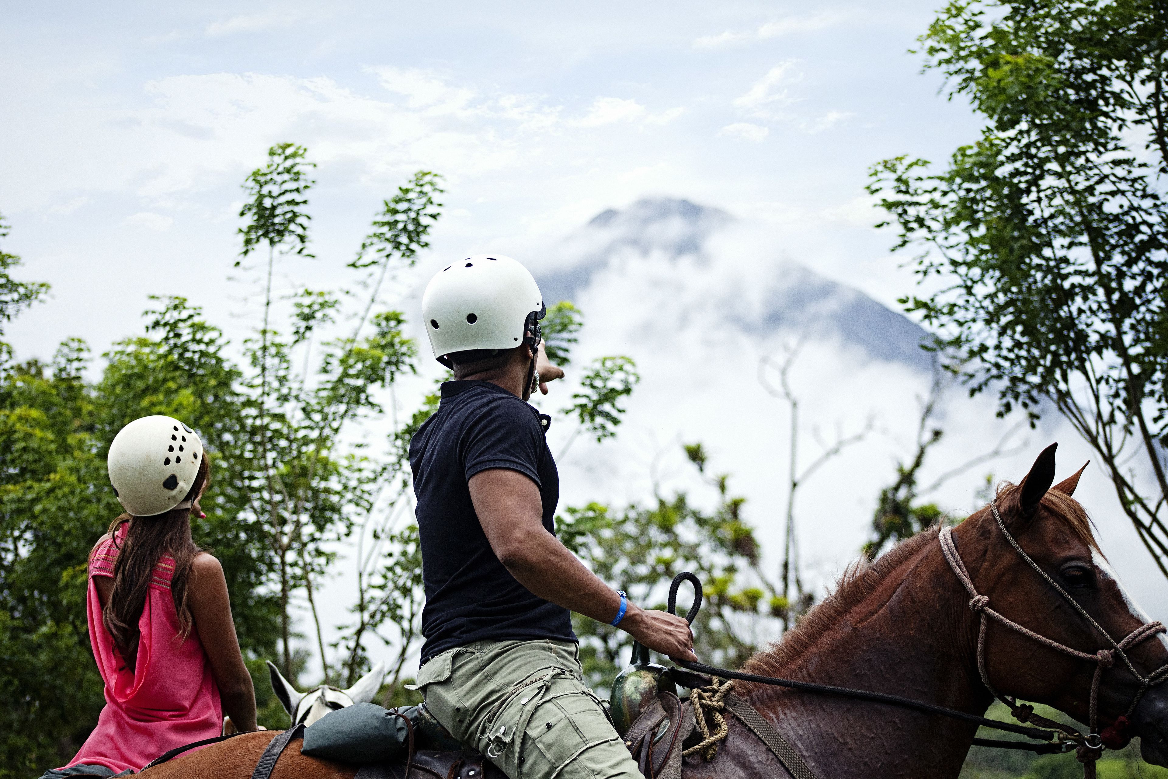 Une personne à cheval, avec un paysage montagneux en arrière-plan.