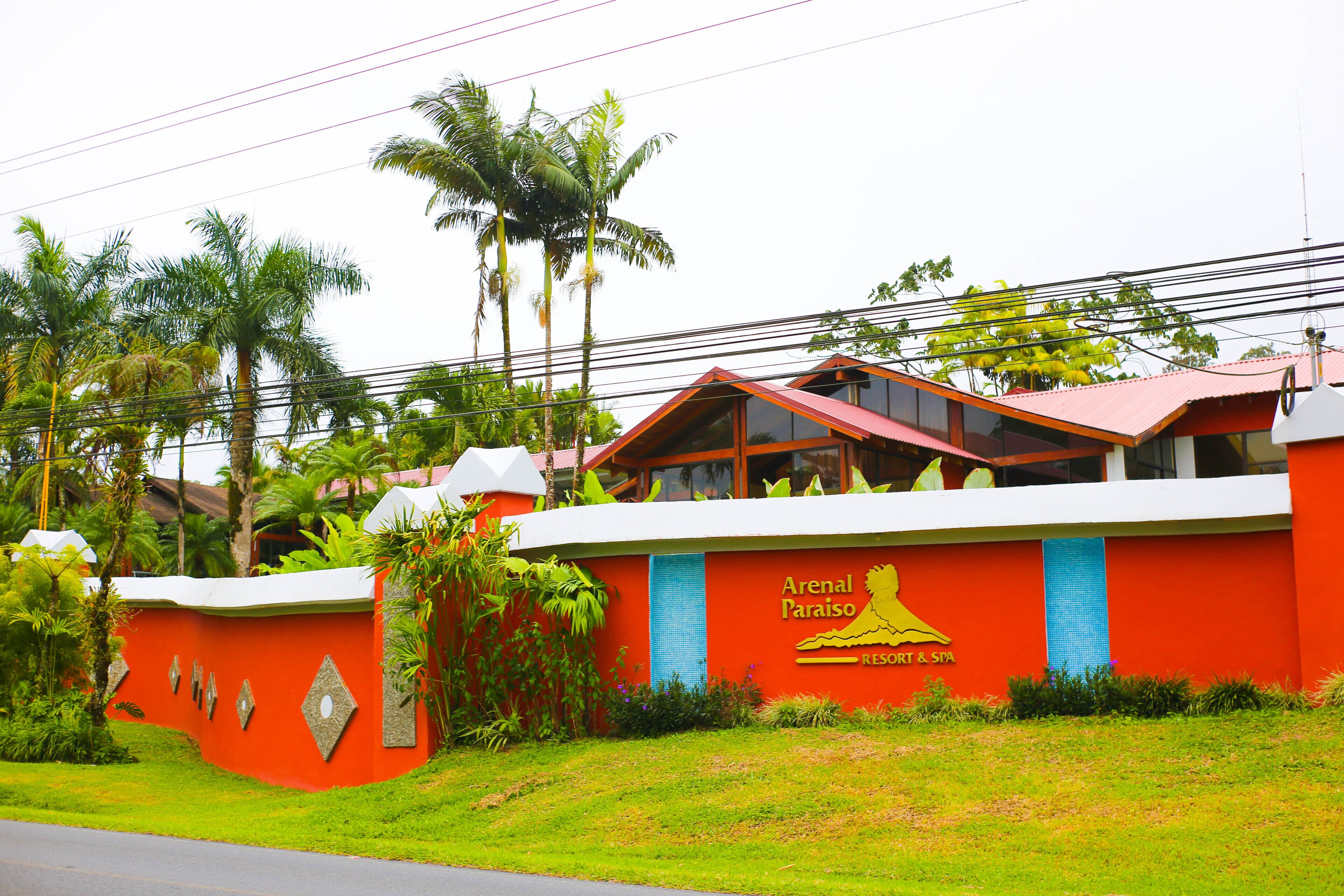 A red building with a sign reading "Arenal Paraíso Resort & Spa".