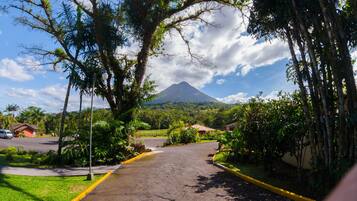 A road leading to a mountain with a view of a residential area and a parked car.