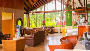 A spacious lobby with a high ceiling, large windows, and a reception desk.