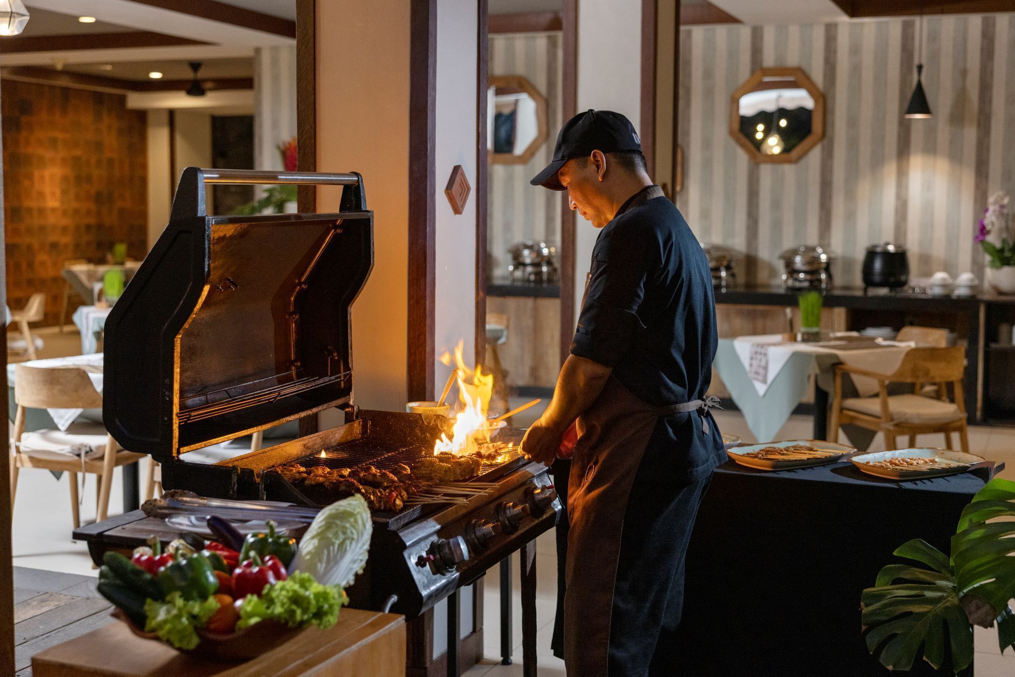 Un chef preparando comida a la parrilla en una cocina al aire libre de un restaurante.