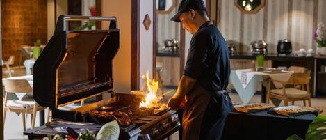 Un chef preparando comida a la parrilla en una cocina al aire libre de un restaurante.