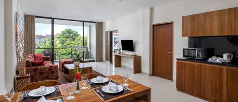 A modern living room with a dining area, large windows, and a kitchen with wooden cabinets.