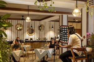 A musician performing at a restaurant with tables, chairs, hanging lights, and decorative mirrors.