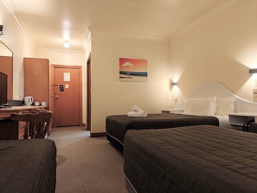 A hotel room with two beds, a desk with a chair, a coffee maker, and a painting on the wall.