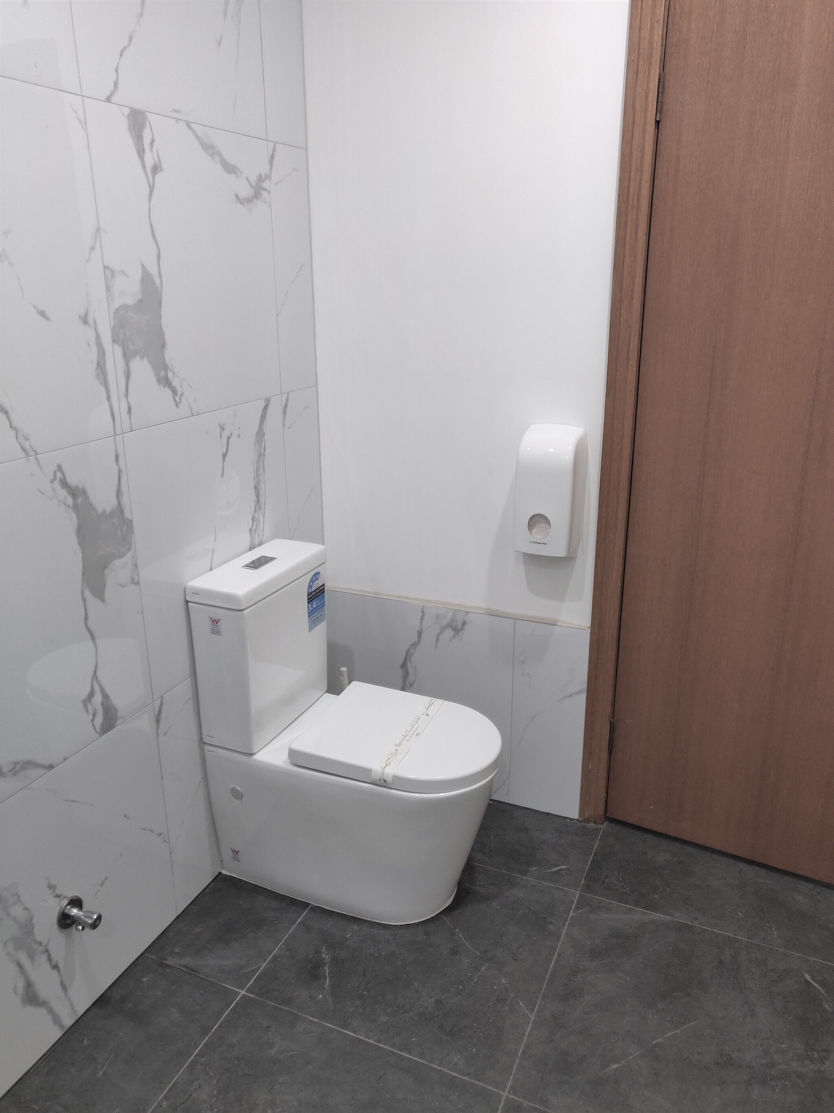 Un baño con inodoro, secamanos y paredes con diseño de mármol.