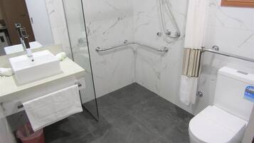 A bathroom with a white sink, mirror, and toilet. There is a glass shower enclosure with a handheld showerhead.