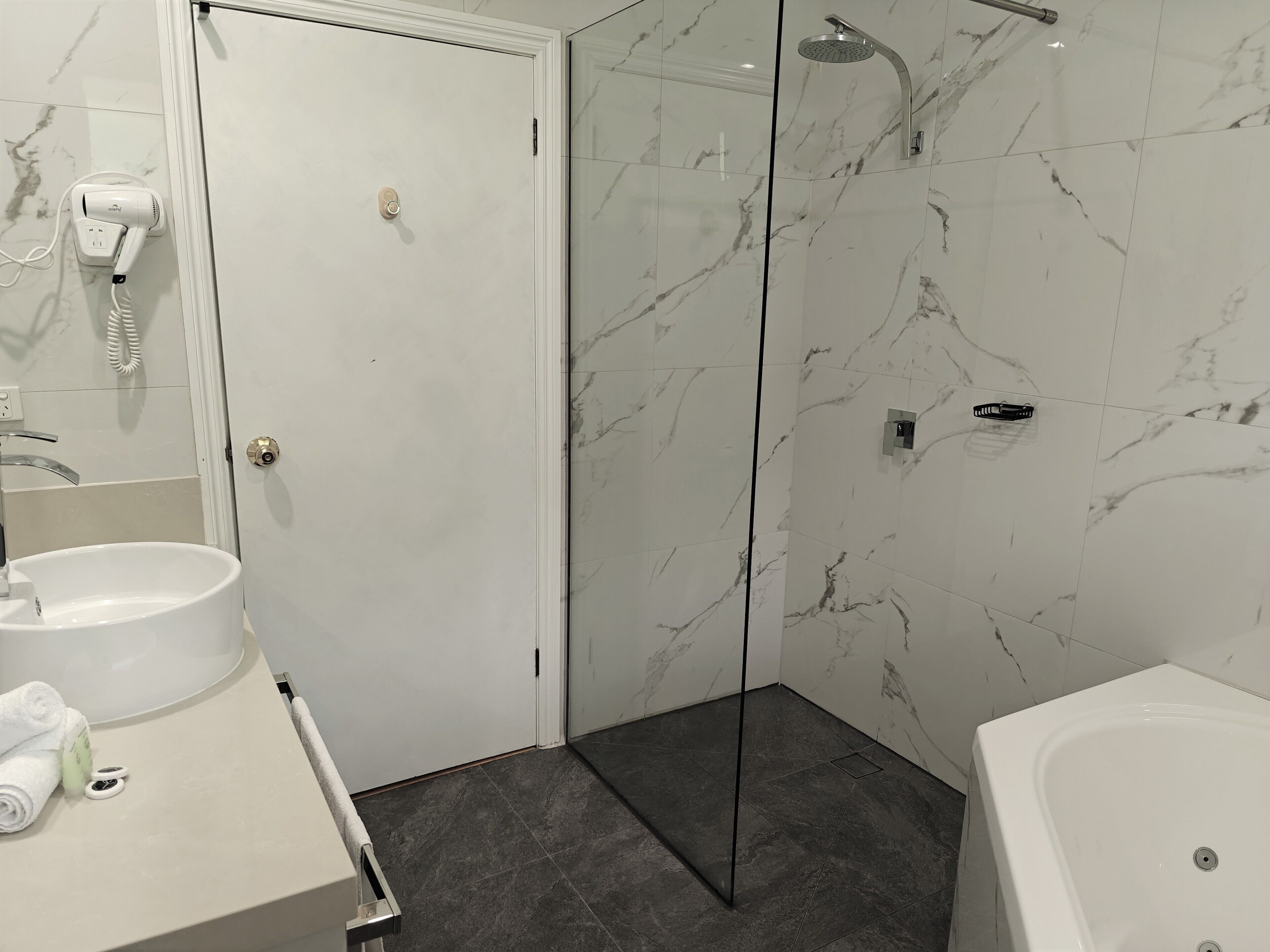 Un baño con un lavamanos blanco, cabina de ducha de vidrio y una bañera blanca.