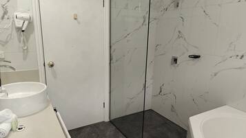 Un baño con un lavamanos blanco, cabina de ducha de vidrio y una bañera blanca.