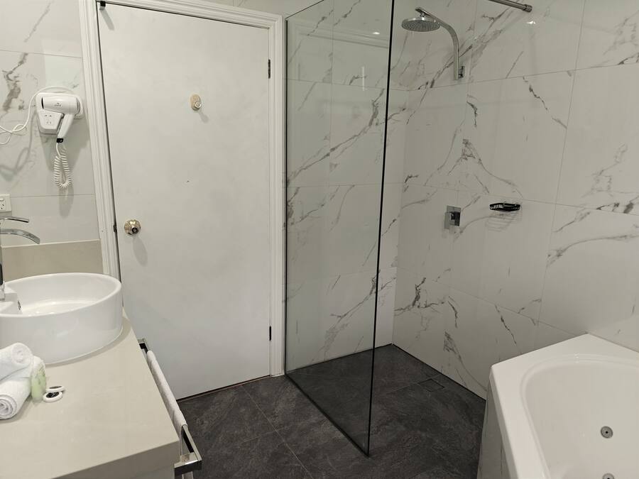 Un baño con un lavamanos blanco, cabina de ducha de vidrio y una bañera blanca.
