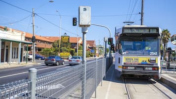 A tram with a sign reading "VIA COLLINS ST 112" and a "MOTEL ENTRANCE" sign in the background.