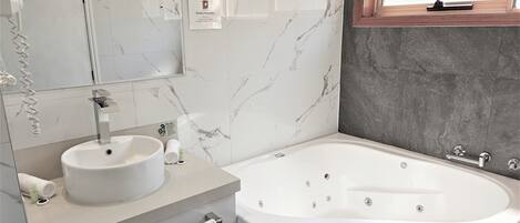 Un baño moderno con tocador de mármol, una bañera independiente y un ventanal con vistas.