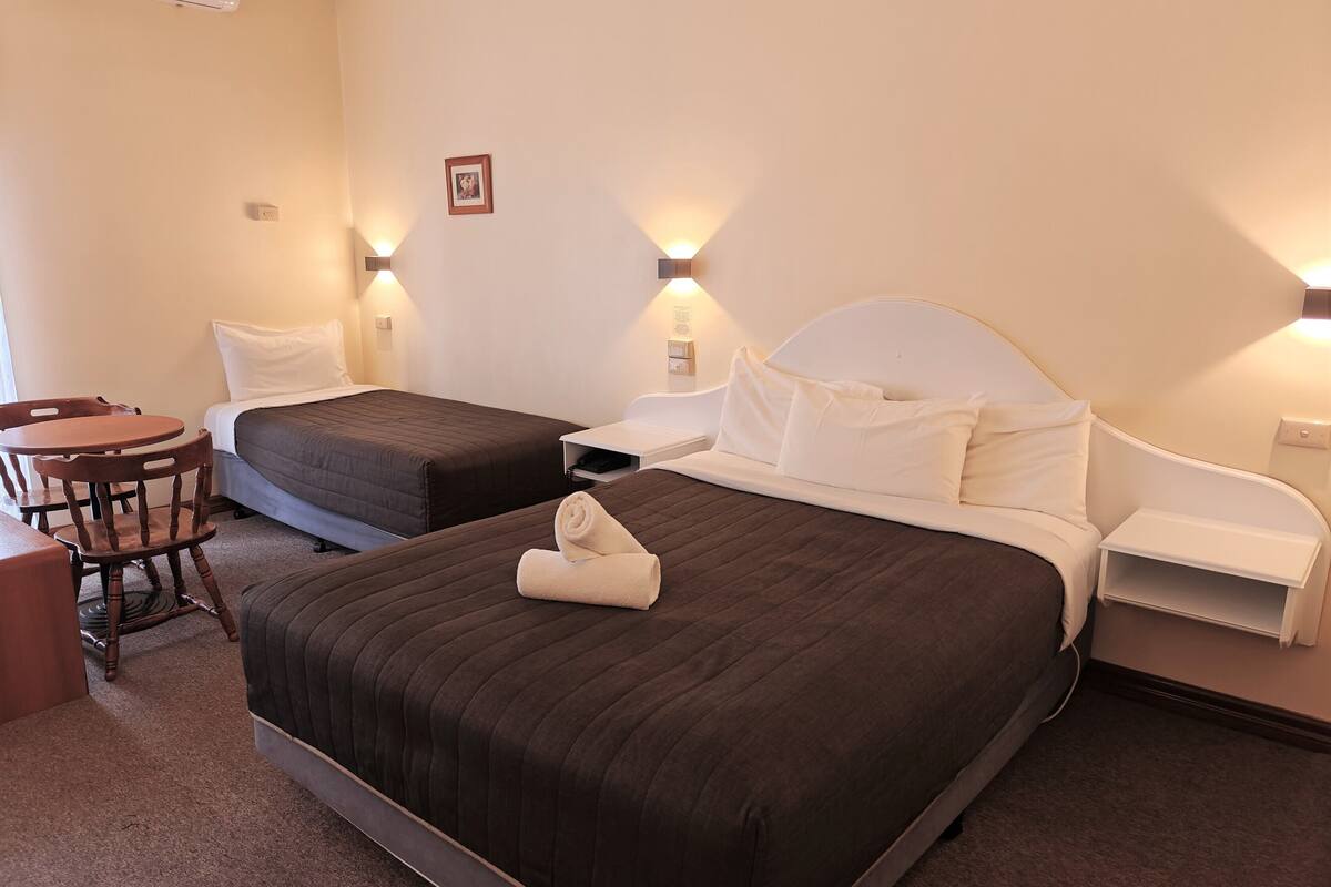 A hotel room with two beds, a desk, and a chair.