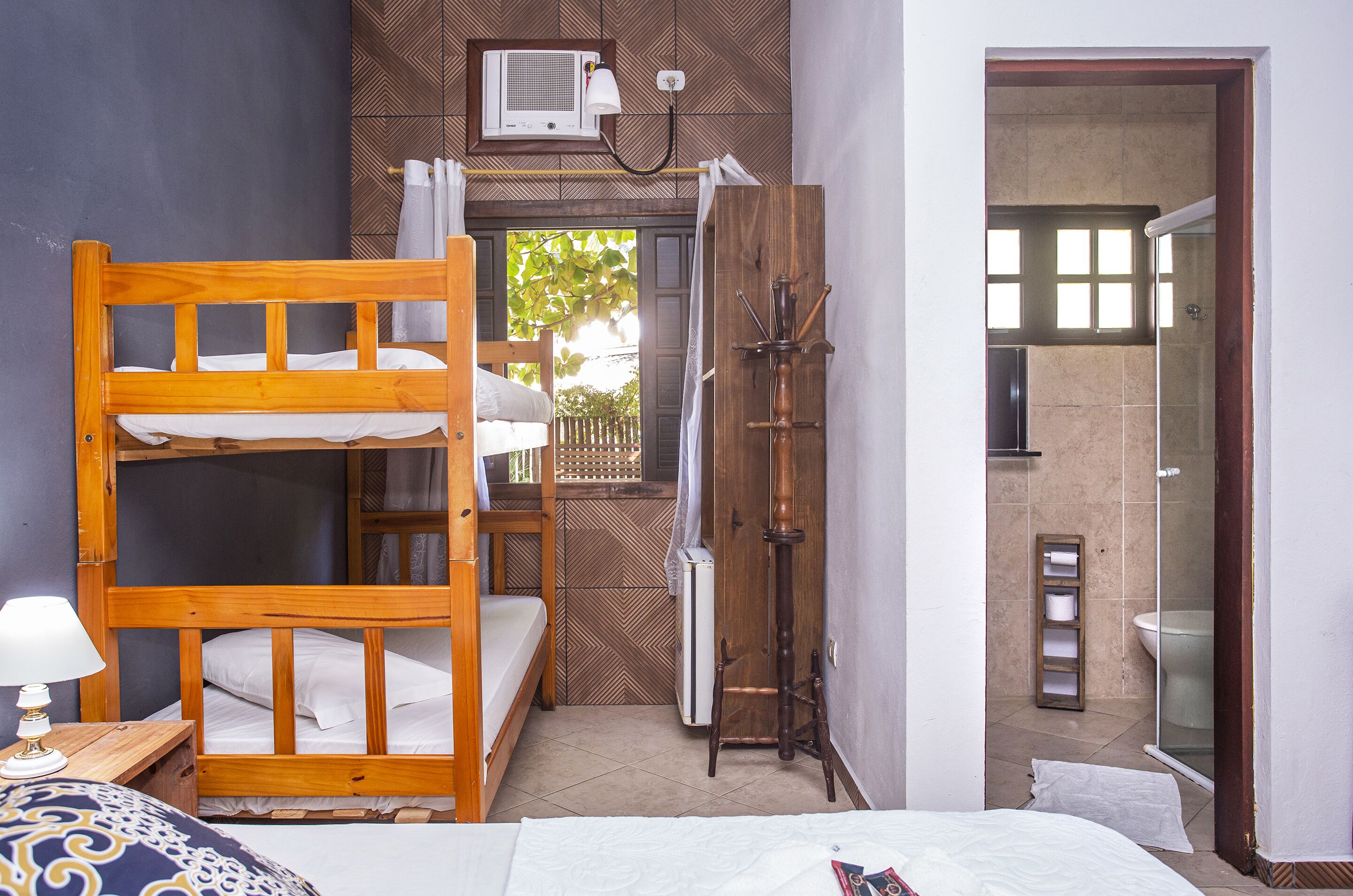 A room with a bunk bed, a bedside table with a lamp, a radiator, and a shower area.