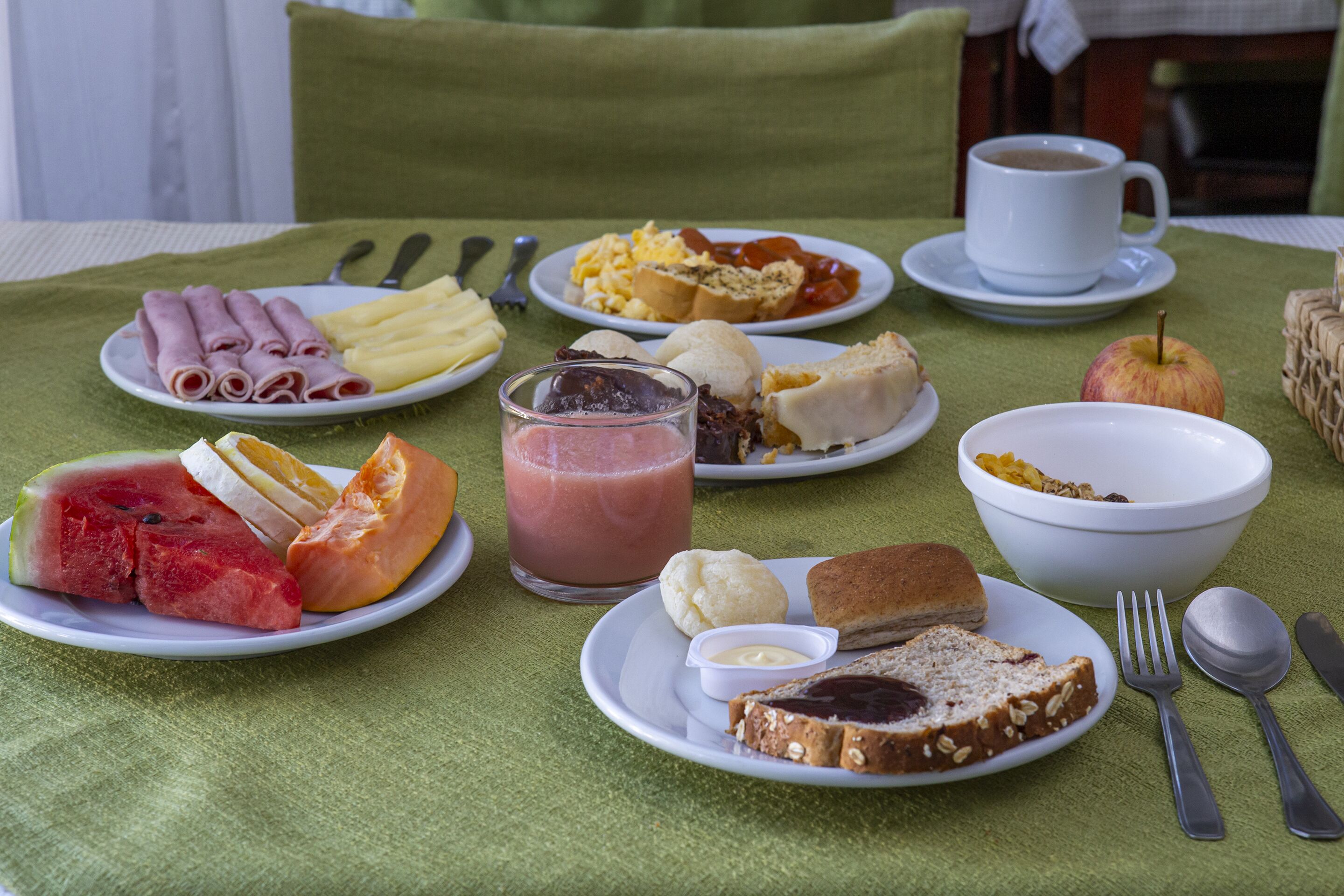 Una mesa de desayuno con platos de comida, un vaso de jugo y una taza de café.