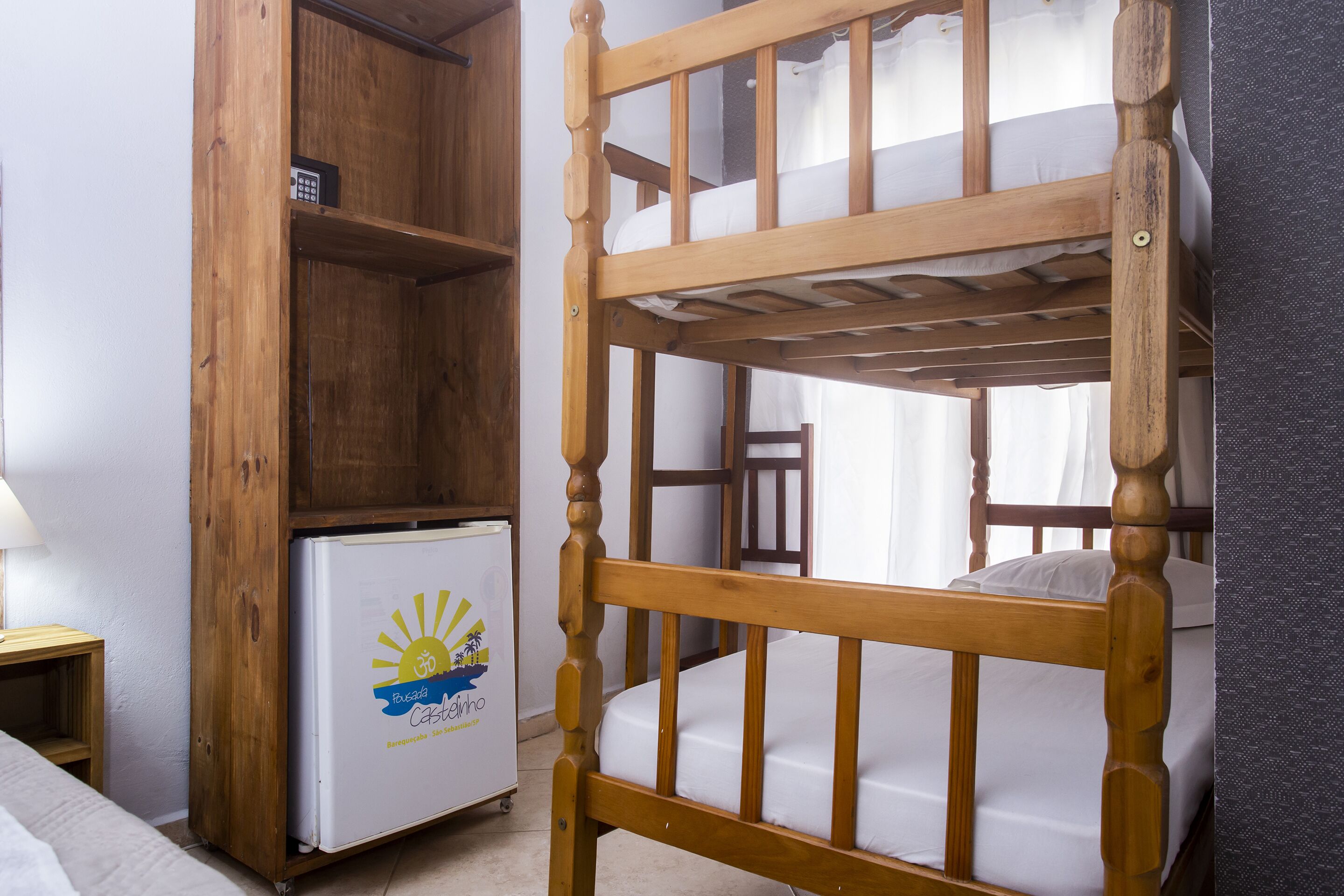 A bunk bed with a wooden frame and a small refrigerator with a logo.