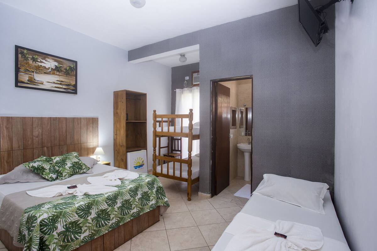 Ein Hotelzimmer mit zwei Betten, einem hölzernen Kopfteil, einem Bild an der Wand und einem durch eine offene Tür einsehbaren Badezimmer.