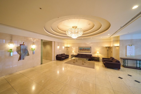 A spacious lobby with a large chandelier, comfortable seating, and a polished floor.