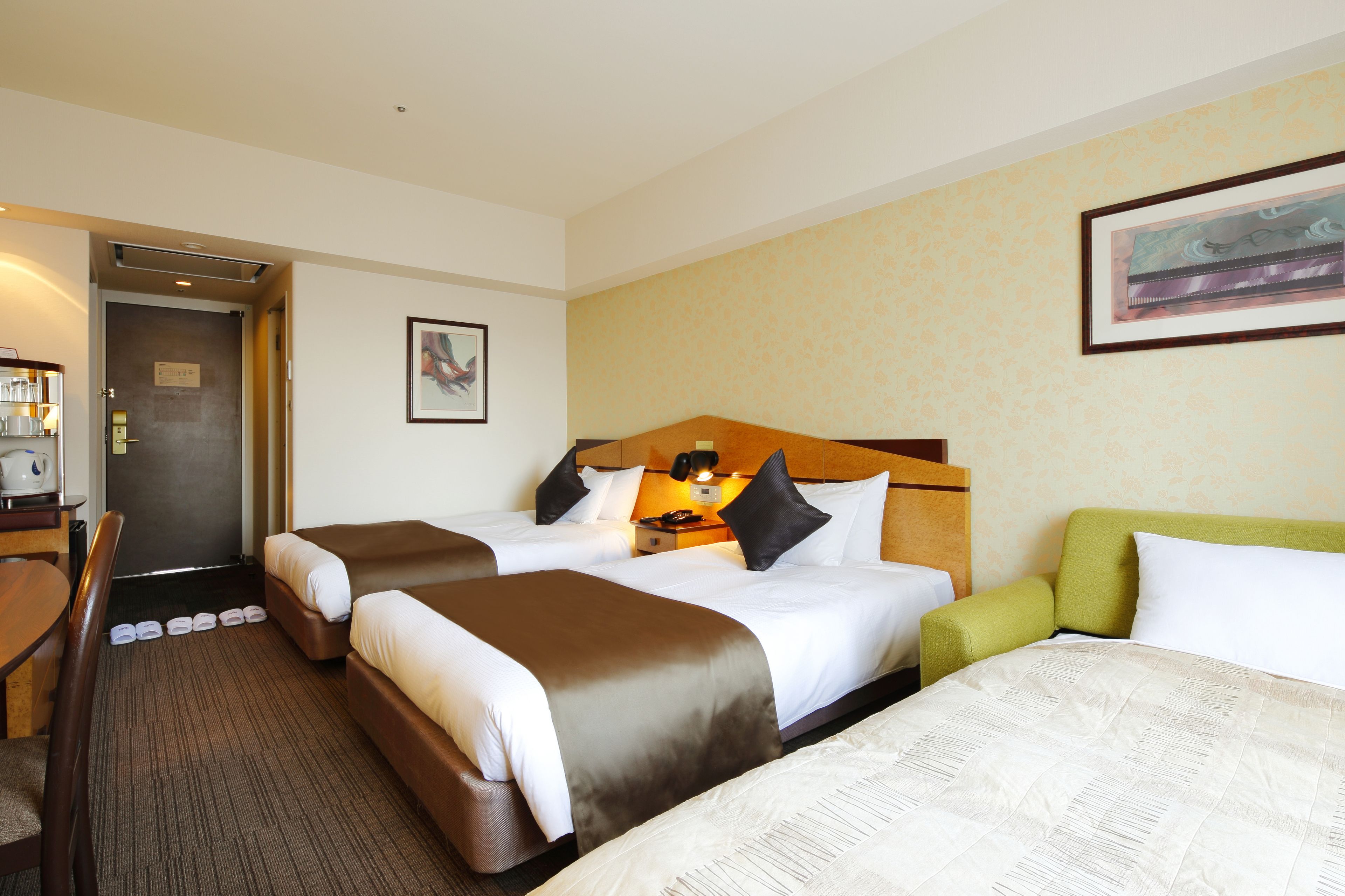 Une chambre d’hôtel avec deux lits, un bureau et une chaise.