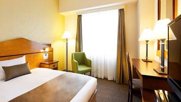 Een hotelkamer met een groot bed, een bureau, een stoel en twee lampen.