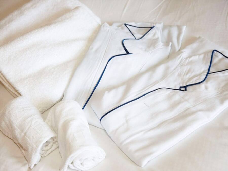 Un juego de bata y toalla blancos, ordenados sobre una cama.