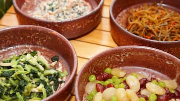 Four bowls of food on a wooden table.