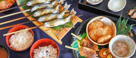 Una variedad de platos, incluyendo pescado a la parrilla, arroz y otras guarniciones sobre una mesa.