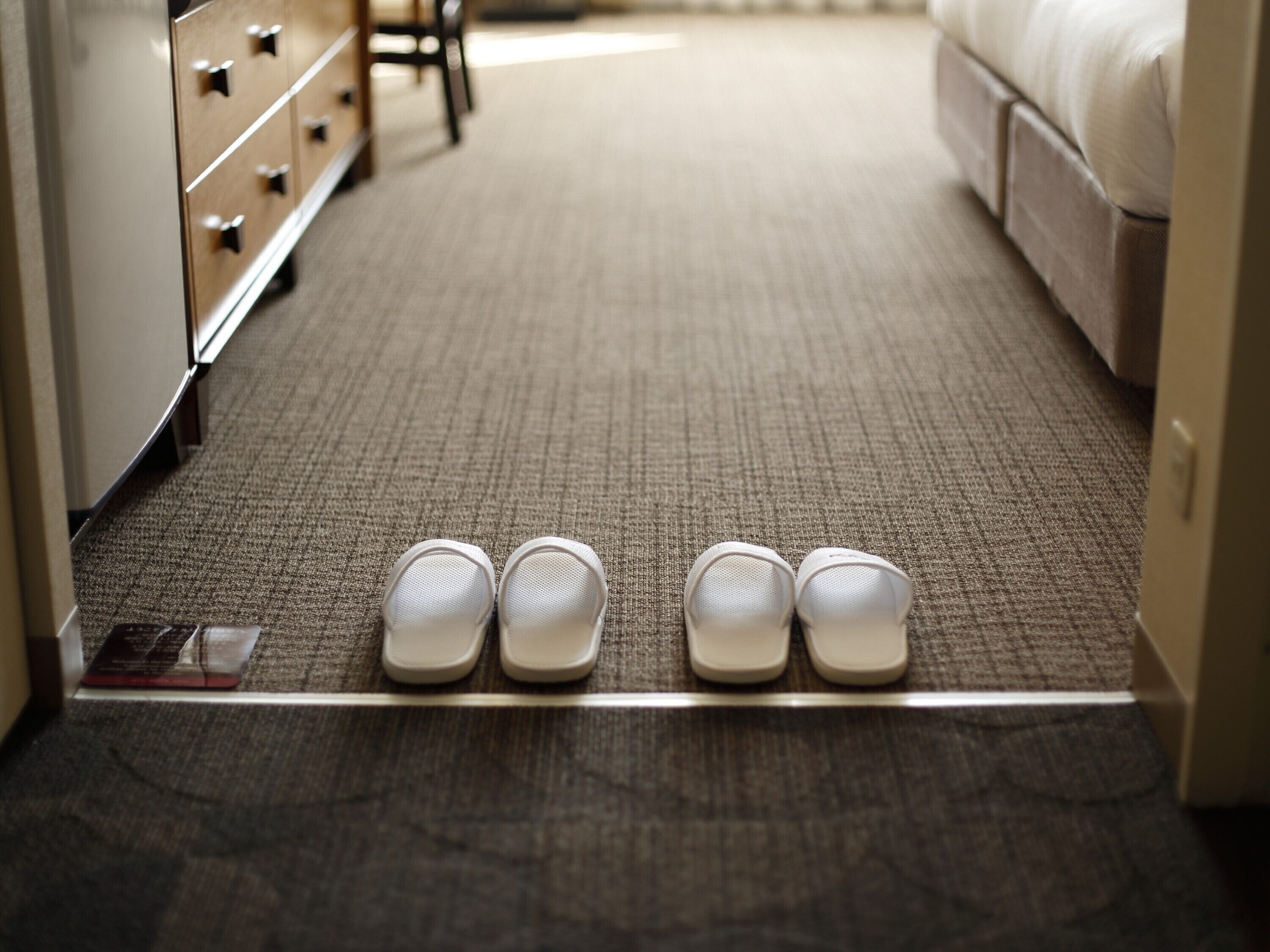 Una habitación de hotel con piso alfombrado, una cama y un aparador con cajones.