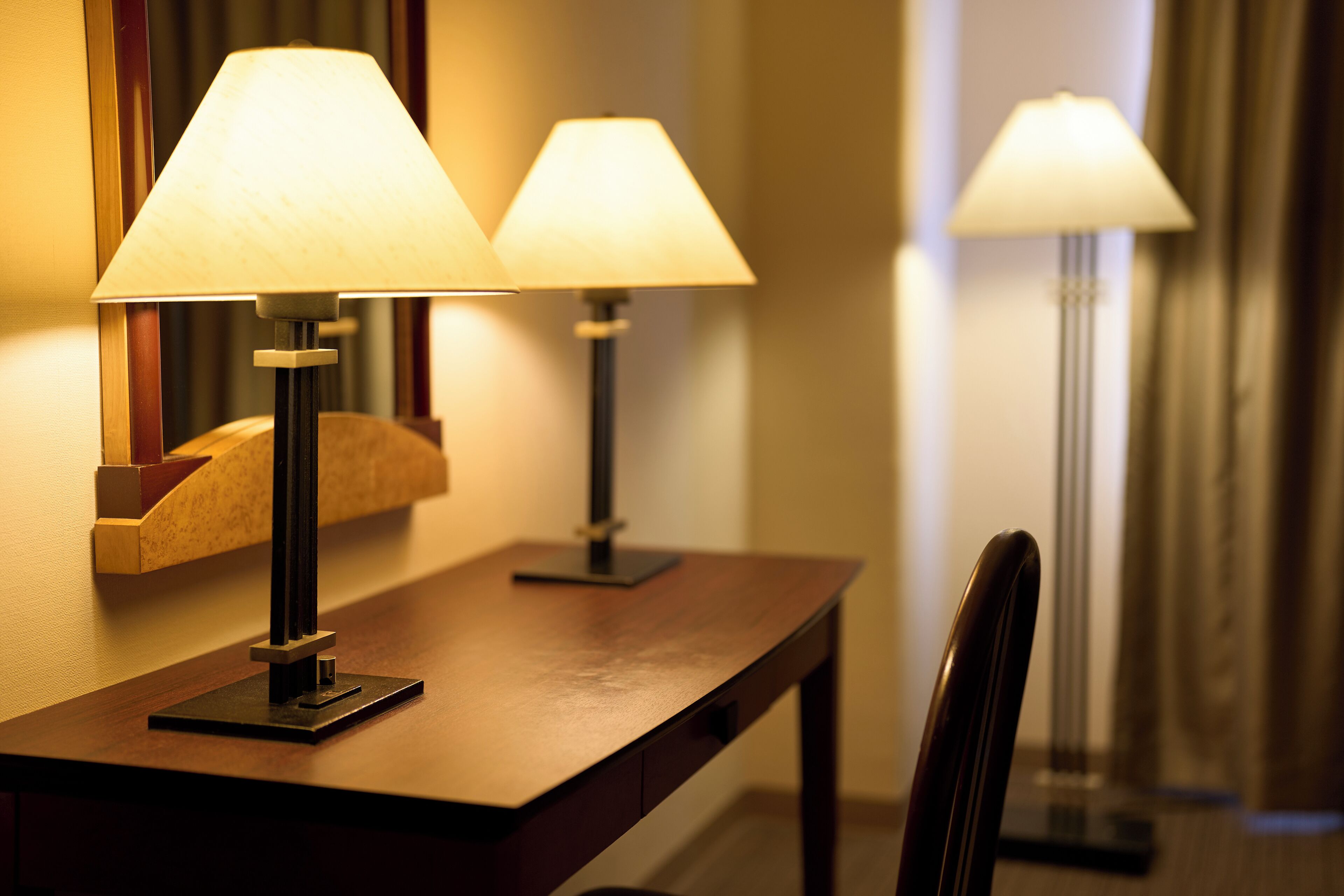 Un mostrador de recepción de hotel con dos lámparas, una silla y un espejo.