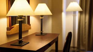 A hotel reception desk with two lamps, a chair, and a mirror.