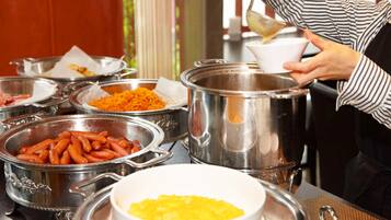 A buffet setup with various food items in metal containers and bowls.