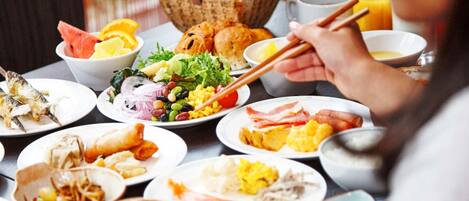 A dining table with various dishes including fish, salad, and eggs, and a hot pot in the background.