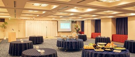 A conference room with multiple round tables, a stage with a podium, and a screen displaying "RESOL".