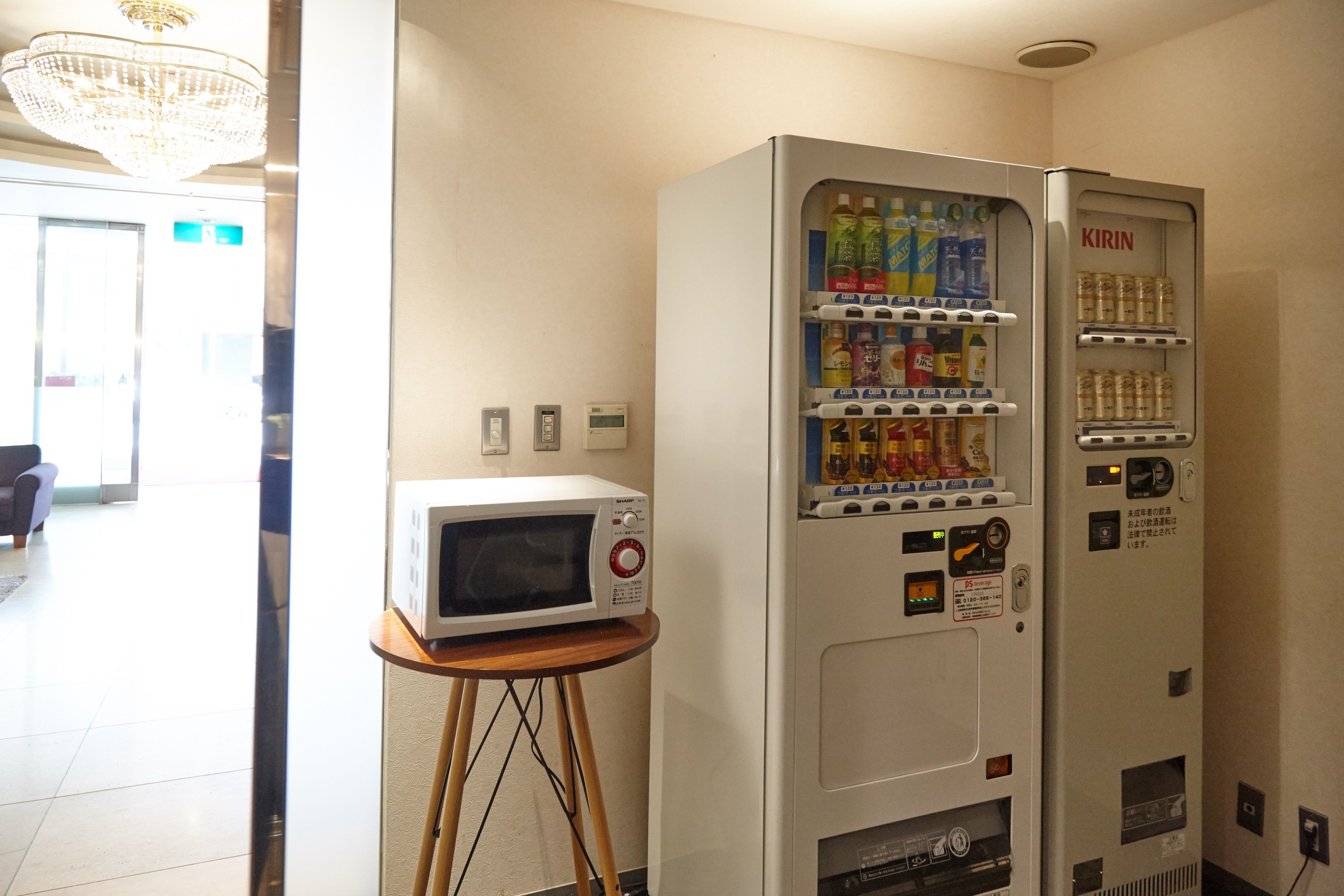 A vending machine with beverages and snacks, a microwave, and a small table with a microwave on it.