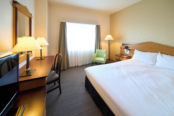 A hotel room with a large bed, a desk with two lamps, a chair, and a nightstand with a lamp. - Hotel Resol Gifu (Gifu)