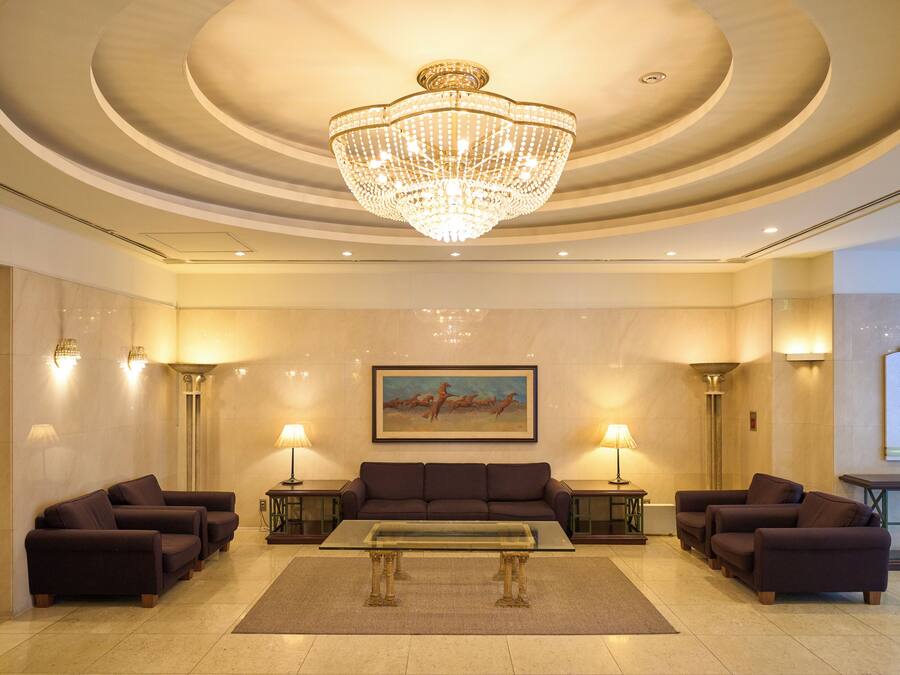 A lobby with a chandelier, sofas, a coffee table, and wall-mounted lamps.