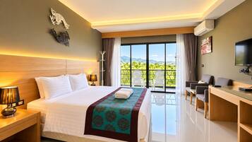 A hotel room with a large bed, a desk, a TV, and a balcony with a view of the mountains.